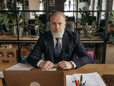 Man in a Black Suit Jacket Sitting at the Table