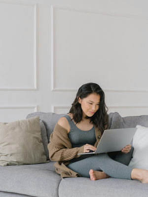 A Virtual Assistant Sitting on a Couch while Busy Working on Her Laptop