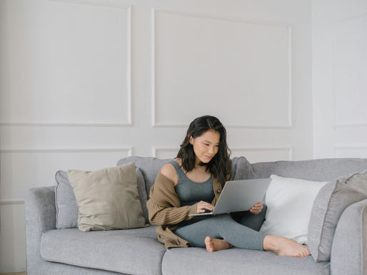 A Virtual Assistant Sitting on a Couch while Busy Working on Her Laptop