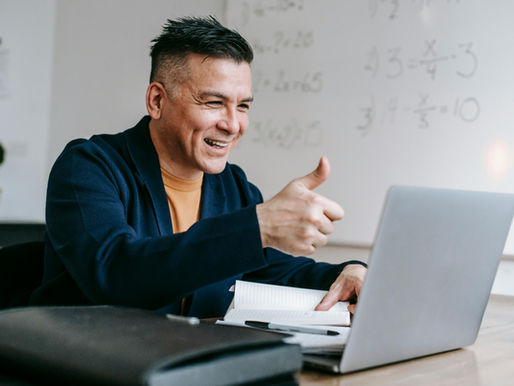 Business Owner gives thumbs up while video conferencing from home office.