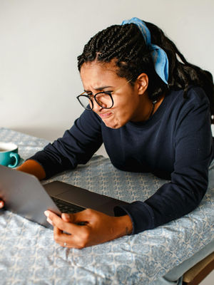 A Virtual Assistant expressing frustration while using a laptop at home.