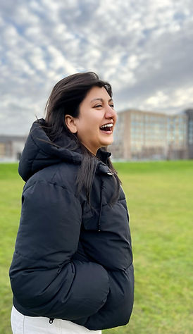 Shonali laughing outdoors, wearing a black puffer jacket