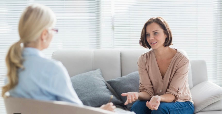 Women talking on couch comfortably to female professional .