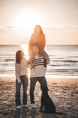 Familie steht mit Hund am Meer
