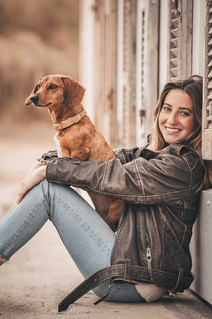 Frau sitzt mit Hund am Strand