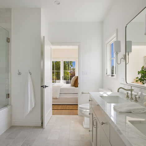 Primary bathroom with a double vanity, brass fixtures, and marble shower, custom home builder Los Angeles
