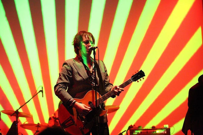 a rock and roll band on stage performing with liquid light projections