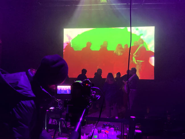 liquid light artwork, projection and photography, a projectionist at work, man projecting liquid on the wall, a band playing live with psychedelic projections. A festival film screening