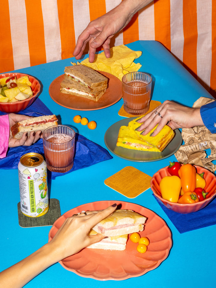 pop coloured table setting with food and sandwiches and hands picking food 