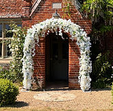 7ft Artificial Floral Wedding Arch. Filled with a variety of white flowers and greenery to create a stunning full backdrop. We can also add in your accent colours to match your theme.