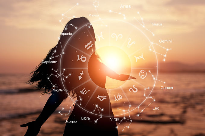 Woman standing in open field with arms outstretched, overlaid with an astrological wheel — symbolizing spiritual freedom, cosmic alignment, and life purpose clarity