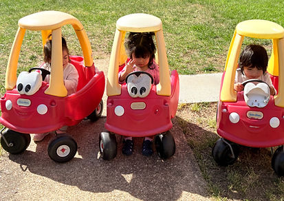 Toddlers riding Little Tikes cars during outdoor play at Bright Hands Academy