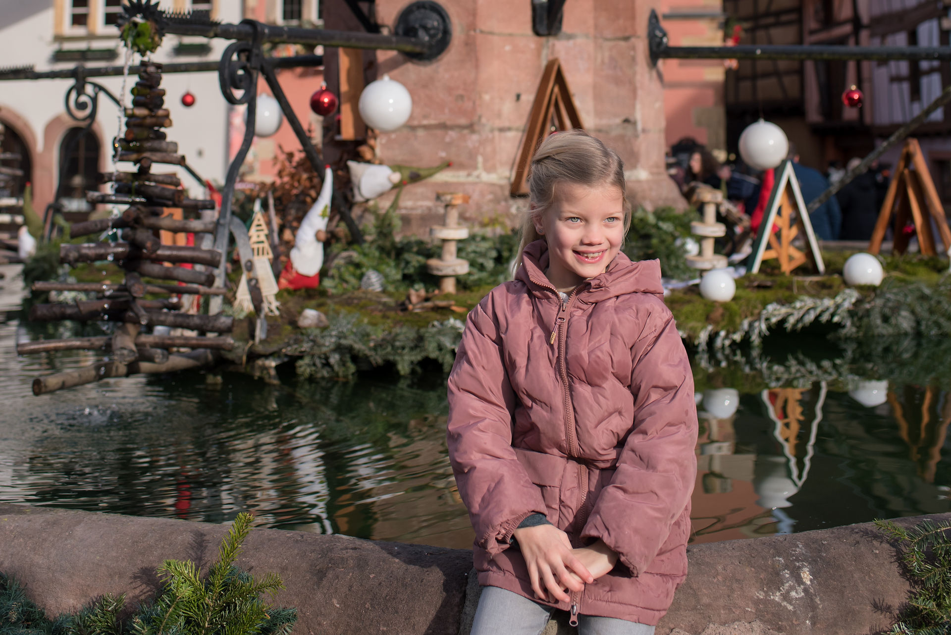 Mooiste dorpen Elzas. Elzas - de Elzas - Elzas Frankrijk - Kerstmis - kerstmarkt elzas - reis kerstvakantie - elzas vakantie - uitjes kerstvakantie - Meisje aan de fontein in Equisheim