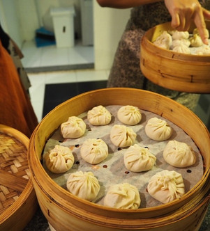 Close-up of bamboo steamers filled with handmade dim sum dumplings before steaming.