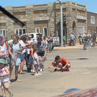 Boy on the ground plays with something while people watch outside.