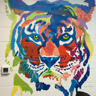 Colorful painted tiger head on wall with multi-colored abstract design.