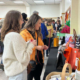 Two women at a craft fair looking at items on display. PEAF