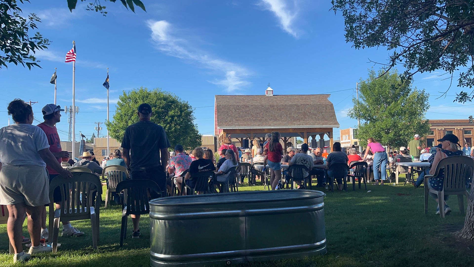 People gathered outdoors enjoying a sunny day, All-School Reunion, eating and socializing.
