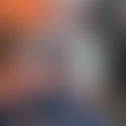 Baby in floral bib held by person, looking curiously at the camera, PEAF