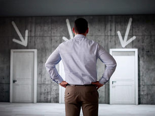 A man looking at 4 white door.