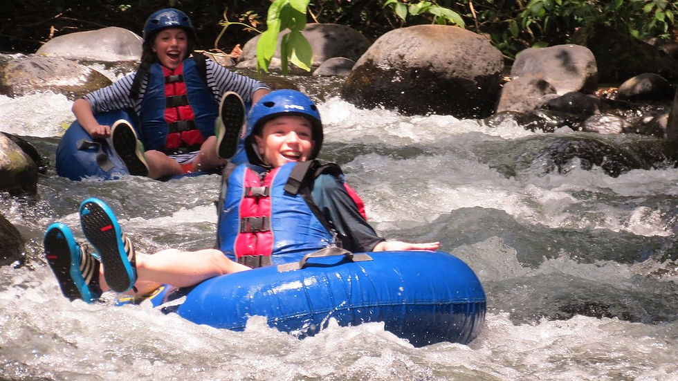 A child in a tube floating down a river smiling