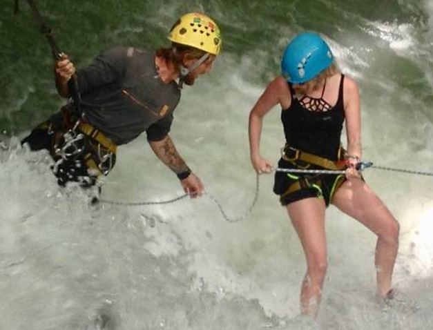 Person rapelling down a waterfall with a guide