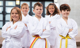 Positive children wearing white sports uniform practicing karate on a street near school.j