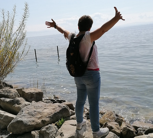 Ich am Ufer des Bodensees mit erhobenen Armen. Freude und Blick auf das Wesentliche.