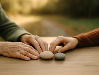 Zwei Hände ruhen auf einem Tisch neben zwei Steinen – Symbol für Gespräch und Vertrauen.