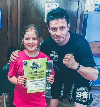 JUNIOR KICKBOXING STUDENT RECIEVING HER BROWN BELT FROM KICKBOXING INSTRUCTOR