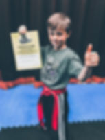 JUNIOR KICKBOXING STUDENT IN KIRKBY WITH HIS RED BELT & GRADING CERTIFICATE