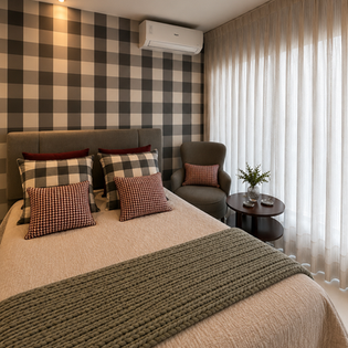 Quarto com papel de parede xadrez e cama arrumada.