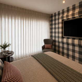 Quarto com papel de parede xadrez preto e branco e TV.
