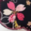 détail d'un patchwork brodé d'une petite femme appuyée sur une tige de fleur