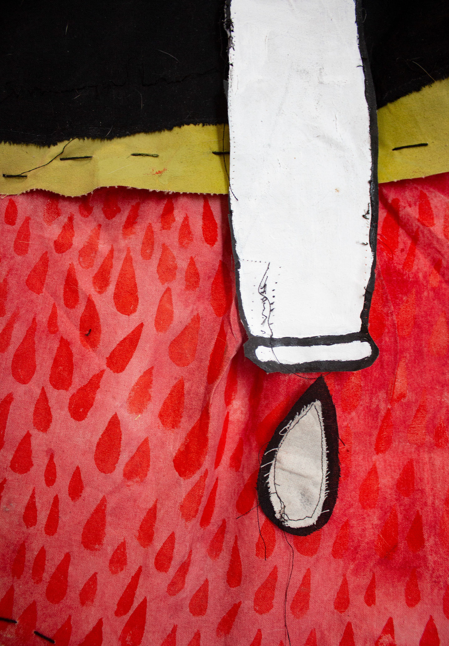 Close up detail image of a black and white pipe that is vertically stitched to a very bright red fabric background. The pipe is dripping a teardrop that is large and graphic. The red fabric Background also has many small red teardrops in it.