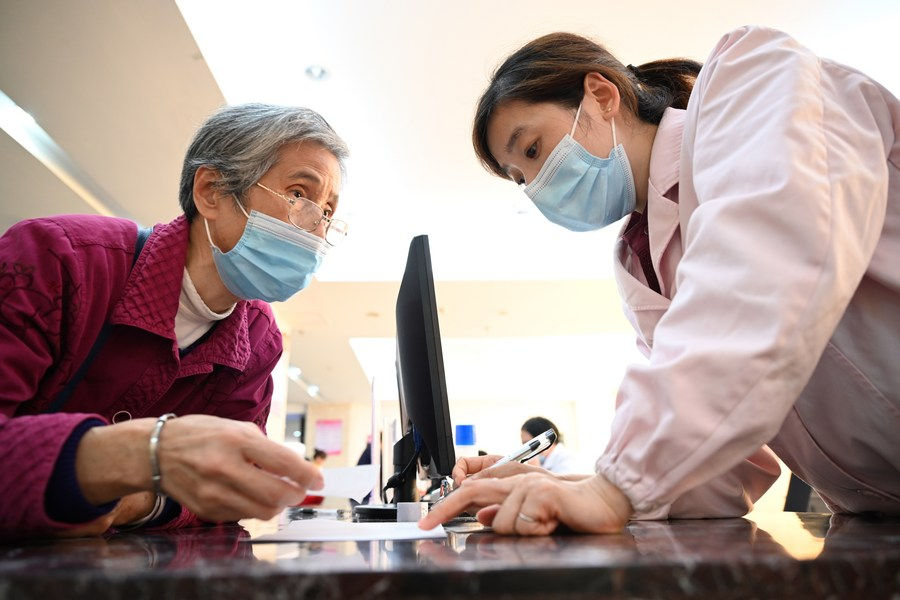 A staff member explains medical insurance policies to a resident at a hospital in Sanming, Fujian Province, Nov. 18, 2020. (Xinhua/Jiang Kehong)