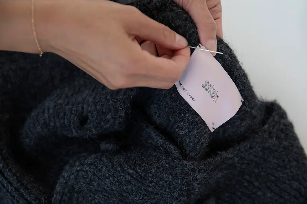 hand stitching SSKEIN brand label onto a cashmere sweater