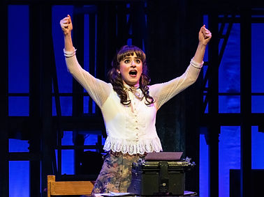 Image of Narée Asherian dressed in an ornate white blouse with her hands above her head.