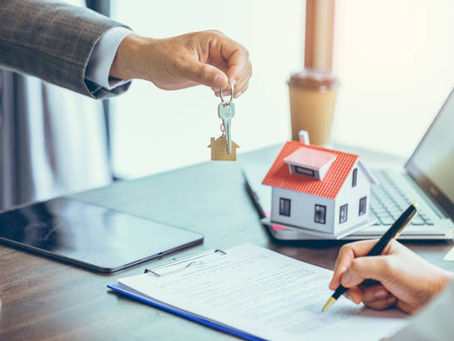 Hand giving house keys during contract signing.