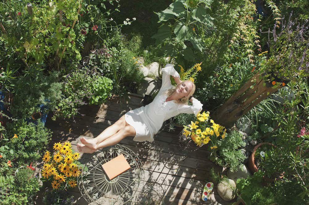 Woman sitting on patio in her garden while relaxing.