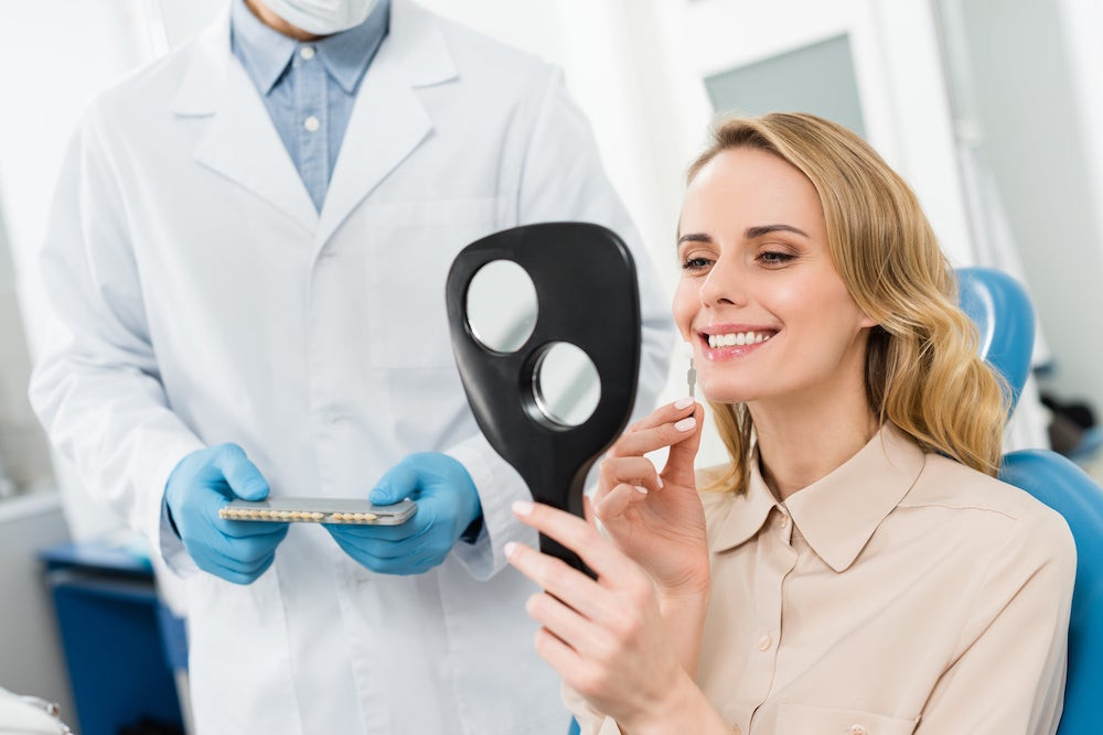 Female dental patient looking at dental implants in the mirror