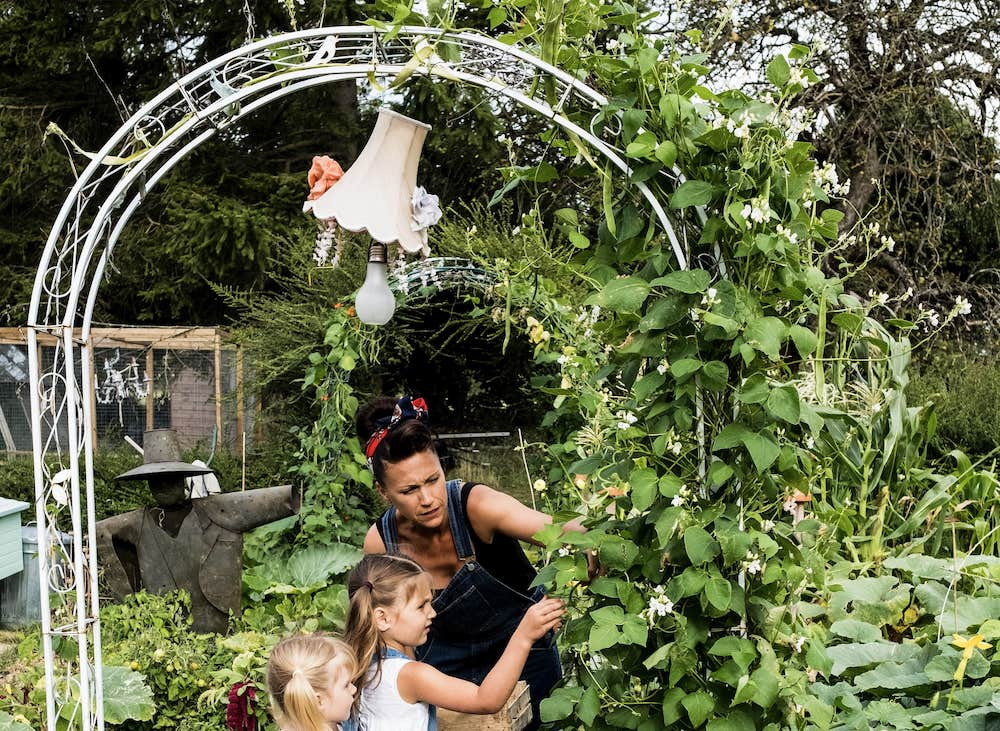 Mom and two kids standing in a garden under an arch