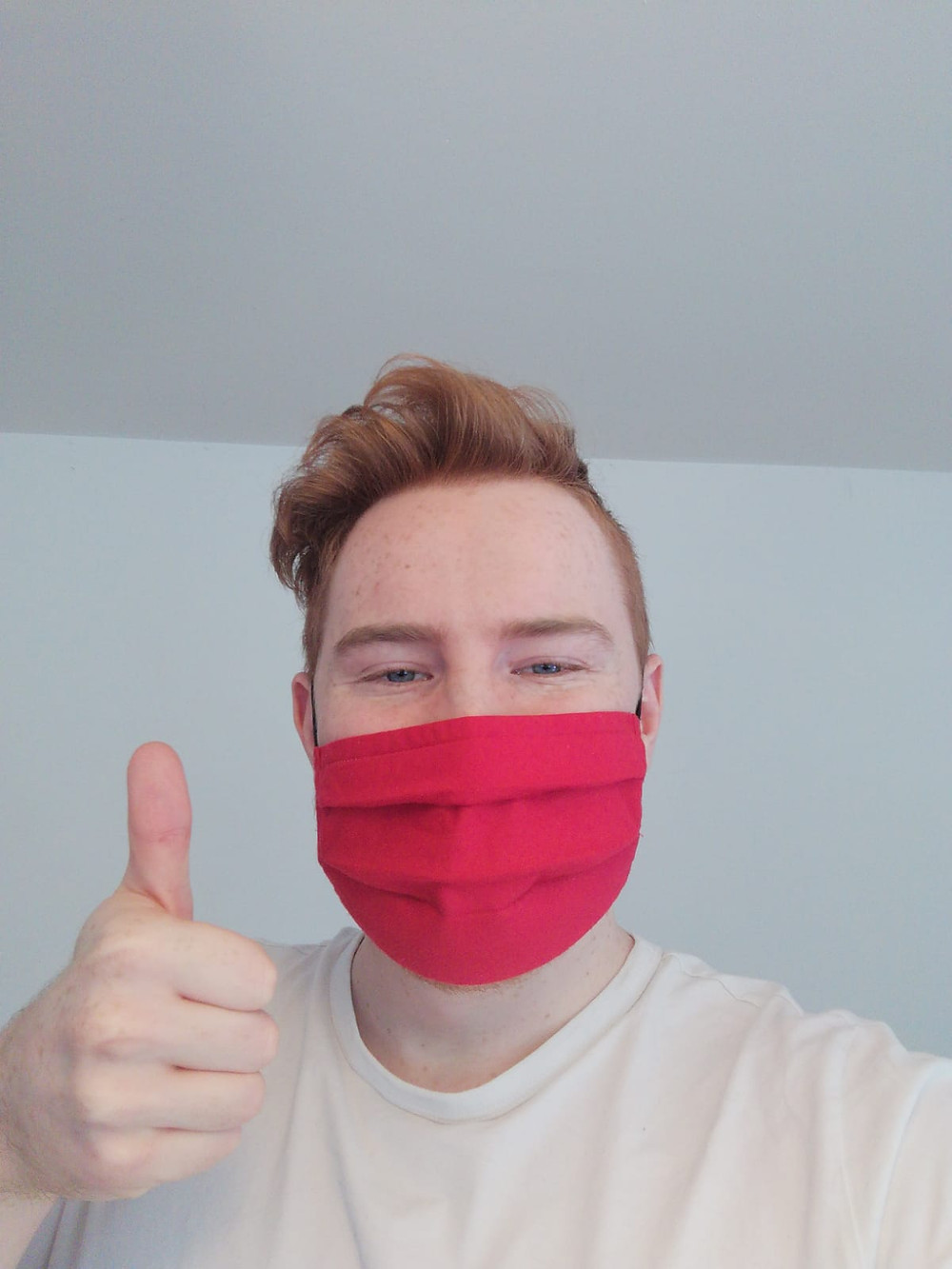 selfie of a man wearing a red mask doing a thumbs up