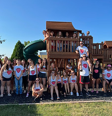 Employee at Thompson Farm posing next to the Wooden Playground
