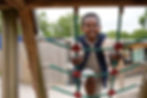 Smiling boy climbing on a rope net at a playground.
