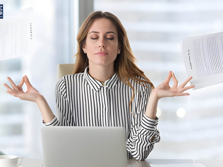 Woman in a striped shirt meditates with closed eyes at a desk, surrounded by hands holding documents. Logo: "Blue Collar Consulting".