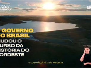 Imagem aérea de barragem ao pôr do sol com textos sobre Transposição do Rio São Francisco e governo do Brasil; intérprete de Libras.