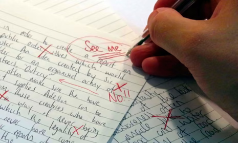 A hand correcting and marking a piece of writing in red ink. One comment says "see me".