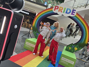 Lumia Photo Booth at Manchester Arndale Centre during a Pride event, with guests posing beneath a colourful rainbow Pride arch.