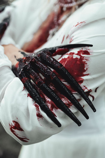 Close-up detail of a bloody, clawed hand with dramatic styling, part of the Maneater fashion photography series.